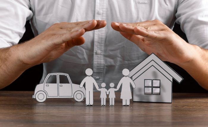 Male forming an arch with his hands over paper family figures