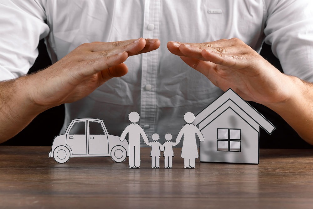 insurance house protection concepts, Hands post protect over house. Male forming an arch with his hands over paper family figures
