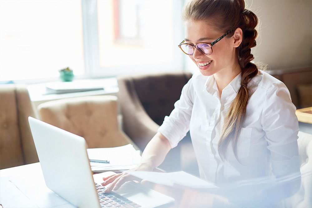 multiple-super-funds-post Lady wearing glasses smiling while sitting operating a laptop